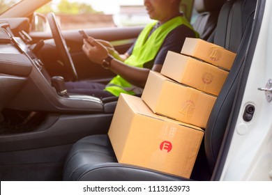 The dispatcher uses the delivery program using a mobile phone. In the van with parcels on the outside of the warehouse.