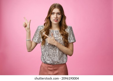 Dispelased Insecure Awkward Young Glamour Rich Girl Dress-up Party Disappointed Dislike Place Cringing Aversion Disgust Pointing Left Questioned Troubled, Concerned Standing Pink Background