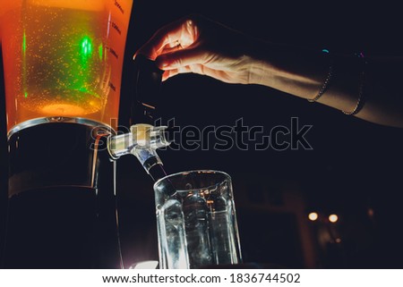 Dispenser and glasses with cold beer on table.