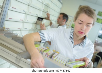 Dispensing pharmacist taking tablets from drawer - Powered by Shutterstock