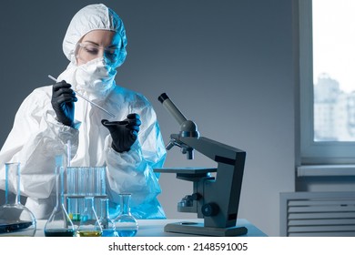 Dispersal of viruses. Member of Institute of Virology. Laboratory research of viruses. Doctor is engaged in dispersal of viruses. Medic in chemical protection suit. Microscope and tube in doctor hand - Shutterstock ID 2148591005