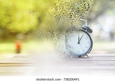 Disperse Effect Retro Alarm Clock On Wooden Table Texture Over Blur Background During Sunrise. Concept Time Is Running Up