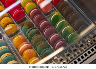 A display case of assorted colored macarons. The macarons are in a clear case and are arranged in rows