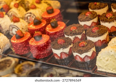 A display case of assorted desserts, including cakes and pastries, with a variety of toppings and flavors.