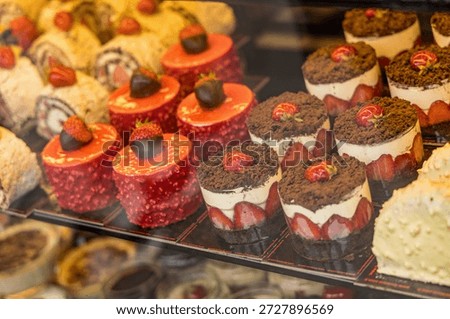 A display case of assorted desserts, including cakes and pastries, with a variety of toppings and flavors.