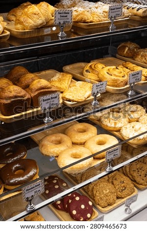 Display case in a bakery filled with fresh donuts, pastries, and croissants.