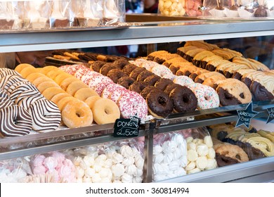 Display of delicious pastries in a bakery with assorted glazed donuts , biscuits and cookies on trays in a shop counter