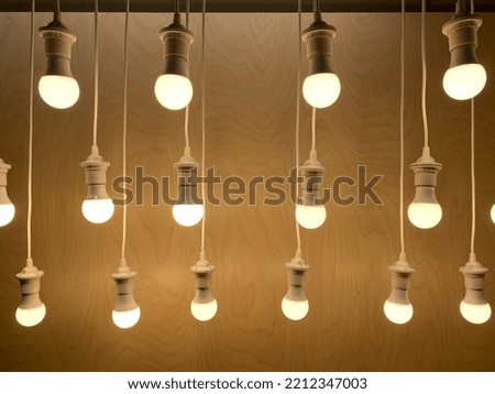 Display of multiple lighted LED bulbs with a wooden background.