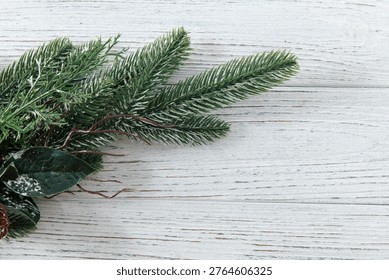A display of pine branches and a pinecone is placed on a wooden surface. The scene captures the essence of winter with a touch of nature.