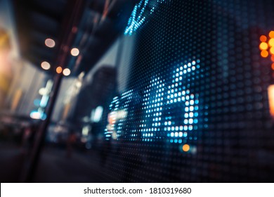 Anzeige von Börsenkursen mit Stadtlampen reflektiert auf Glas