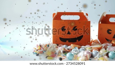 Displaying single orange jack-o-lantern box sitting right of center on white tabletop, with candies. Halloween, pumpkin, candy, flatlay, studio, bokeh, whimsy