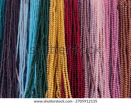 displays a multitude of small beaded strings in various colors and hues.