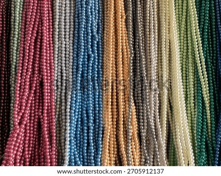displays a multitude of small beaded strings in various colors and hues.