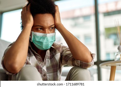 Displeased African American Woman With Face Mask Holding Her Head In Pain And Looking Away At Home. 