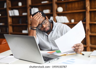 Displeased African-American Man Looking Through Workpapers, Stressed Black Male Employee Reading A Document Bank Statement Sitting In The Office, Has Bad Balance, Bankruptcy, Debt