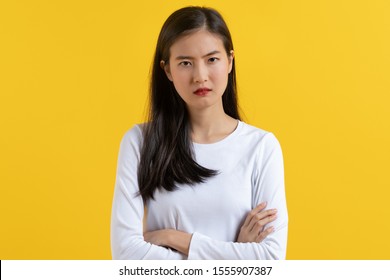 Displeased Asian Teenager In White Casual Shirt Standing In Angry Expression Face. Isolated On Yellow Background In Studio.