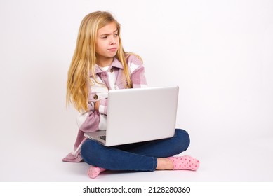 Displeased Beautiful Caucasian Teen Girl Sitting With Laptop In Lotus Position On White Background With Bad Attitude, Arms Crossed Looking Sideways. Negative Human Emotion Facial Expression Feelings.