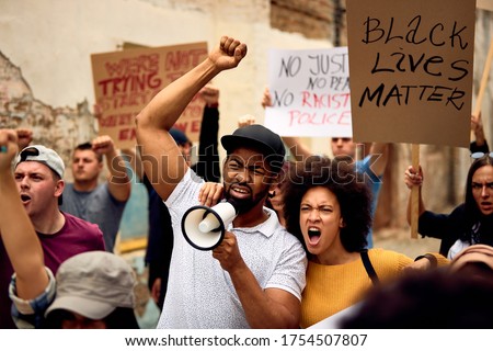 Displeased black couple shouting while marching with group of people on  anti-racism protest.