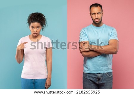 Displeased black lady pointing at herself with wonder, asking whether she is guilty of something, man standing with hands crossed after quarrel, feeling offended, pink and blue background
