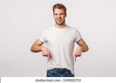 Displeased, Disgusted Picky Handsome Macho Man With Blond Haircut, Bristle, Squinting From Dislike And Reluctance, Pointing Down Aversion, Standing Skeptical, Complain Bad Smell, White Background