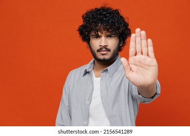 Displeased Dissatisfied Young Bearded Indian Man 20s Years Old Wears Blue Shirt Showing Stop Gesture With Palm Isolated On Plain Orange Background Studio Portrait. People Emotions Lifestyle Concept