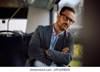 Displeased entrepreneur with arms crossed riding in city bus and looking through the window. Copy space. - Powered by Shutterstock