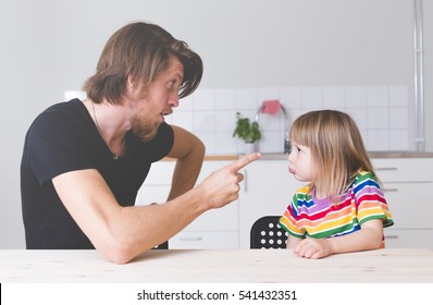 displeased father scolding his kid in preschool age at home, screaming and pointing with finger