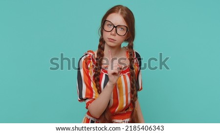 Displeased girl shakes finger and saying no, be careful, scolding and giving advice to avoid danger mistake disapproval disagree warning sign. Redhead teenager child isolated on blue studio background