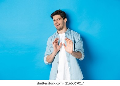 Displeased Man Refusing, Saying No And Cringe From Something Disgusting, Standing Over Blue Background