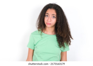 Displeased Upset Teenager Girl With Afro Hair Style Wearing Green T-shirt Over White Background Frowns Face As Going To Cry, Being Discontent And Unhappy As Can't Achieve Goals,  Disappointed Teen 