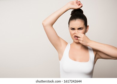 Displeased Woman Plugging Nose With Hand While Looking At Camera Isolated On Grey