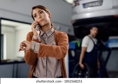 Displeased Woman Talking On The Phone While Waiting For Her Car To Be Repaired At Workshop. 