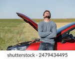 Displeased young adult man breaks down car in the middle of trip on the road calls tow truck to come repair car, roadside assistance, broken down car tired man