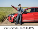 Displeased young adult man breaks down car in the middle of trip on the road calls tow truck to come repair car, roadside assistance, broken down car tired man