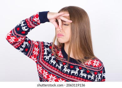 Displeased Young Caucasian Girl Holding A Present Wearing Christmas Sweater On White Background Plugs Nose As Smells Something Stink And Unpleasant, Feels Aversion, Hates Disgusting Scent.