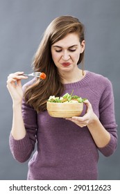 Displeased Young Girl Being Picky At Eating Mixed Green Salad With Cherry Tomatoes As Vegetarian Diet