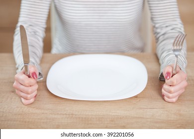 Displeased Young Woman Sitting At The Empty Plate. 