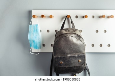 Disposable blue medical mask hanging on a stylish hanger next to the backpack . Healthcare during Coronavirus quarantine. Prevent COVID-19 - Powered by Shutterstock