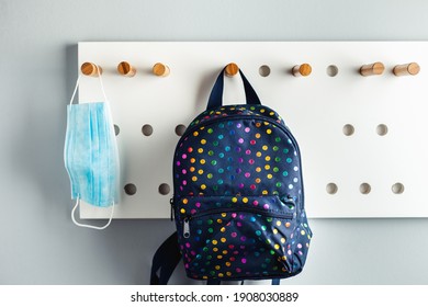 Disposable blue medical mask hanging on a stylish hanger next to the backpack . Healthcare during Coronavirus quarantine. Prevent COVID-19 - Powered by Shutterstock