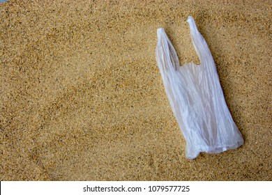 Disposable Carrier Bag, A Single Use Plastic, On Sandy Beach Background. Plastic Pollution Affecting Marine Ecology. Environment Concept. Top View. Copy Space.