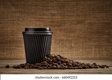 Disposable coffee cup and coffee beans with wooden table - Powered by Shutterstock