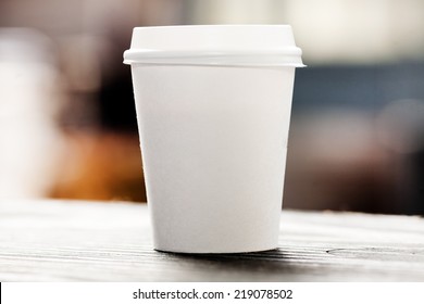 Disposable coffee cup on windowsill with city in background. - Powered by Shutterstock