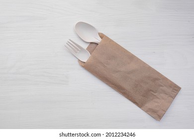 Disposable Cutlery Set Spoon And Fork In Paper Bag On Wood Texture