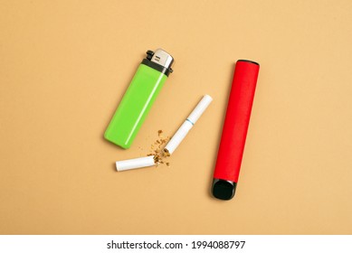 Disposable Electronic Cigarette And Broken Regular Nicotine Cigarette On A Beige Background. Choice Of Modern Smoking Concept