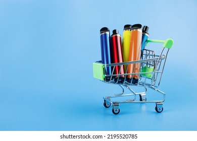 disposable electronic cigarette in a trolley,multicolored vape for smoking in a shopping cart on a blue background,copy space - Shutterstock ID 2195520785