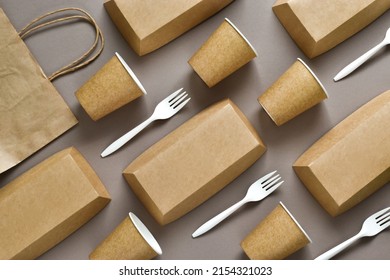 Disposable Environmentally Eco-friendly Food Packaging. Brown Craft Paper Containers, Drink Glasses, Paper Bag And Forks On A Beige Background. Top View, Flat Lay Composition