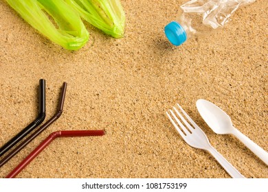 Disposable Fork, Spoon, Water Bottle, Straws And Single Use Carrier Bag On Sandy Beach Background. Plastic Pollution Affecting Marine Ecology. Environment Concept. Top View With Copy Space.