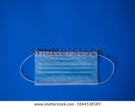 Disposable medical mask on a blue background. Covid-19 protection. Health concept.