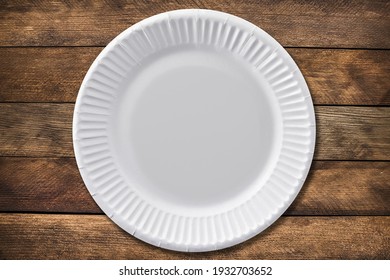 Disposable paper plate on a wooden background. Empty white cardboard plate