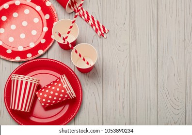 Disposable paper utensils of red and white color on a gray wooden background. Top view.